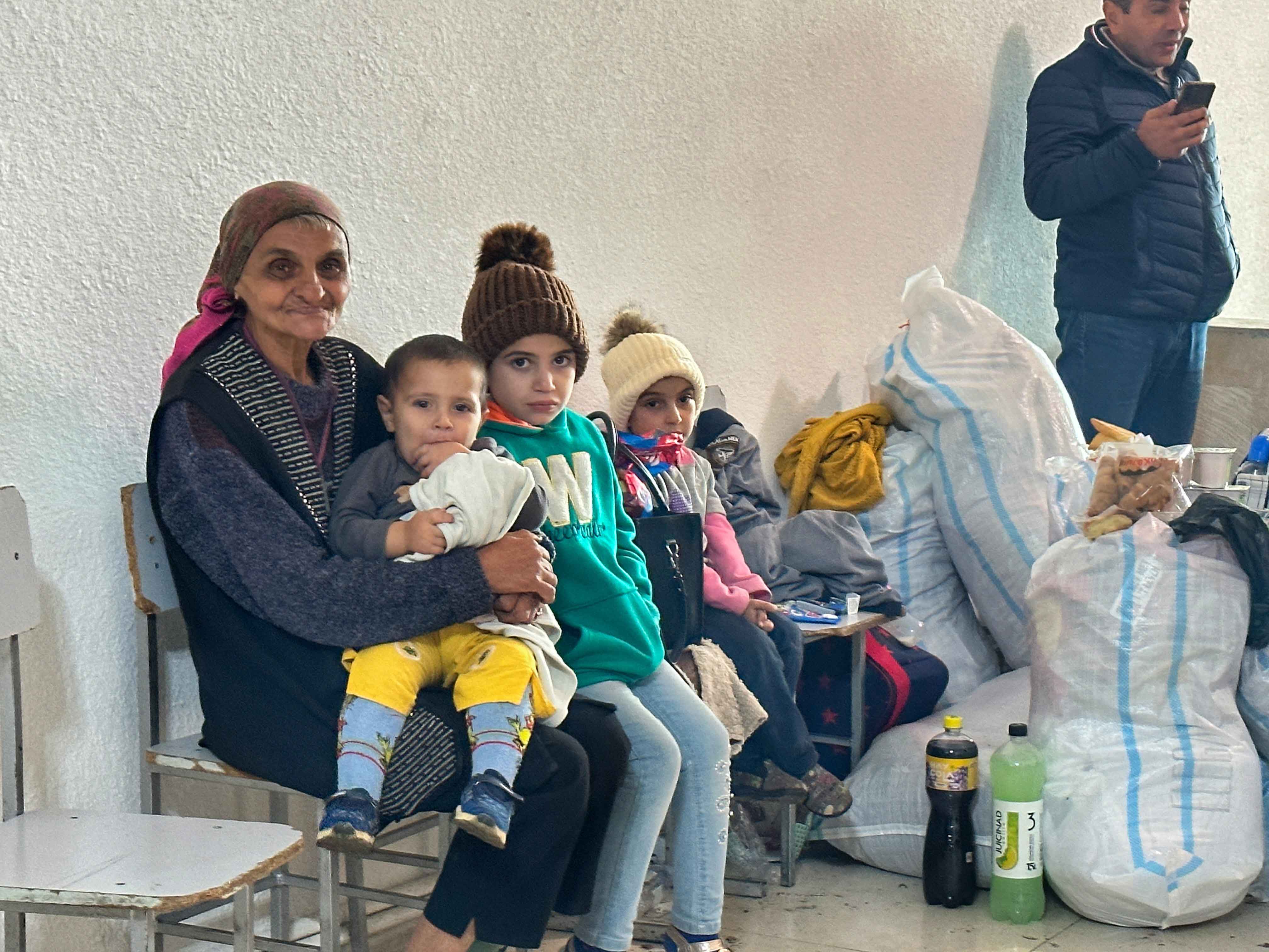 Una mujer y tres niños sentados junto a bolsas y pertenencias durante el éxodo de Artsaj.